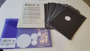 photo of the materials used for The VINCP Minimum Detection Test (white discs that a child can fix against a black background)