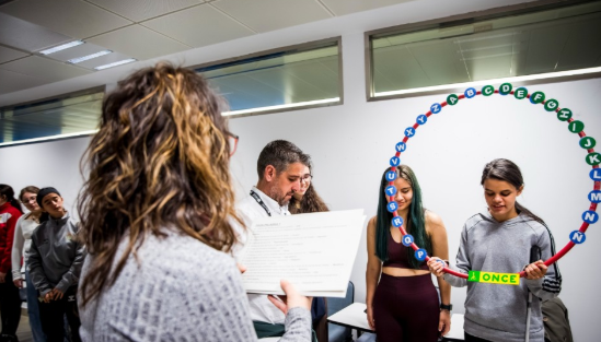 Two student playing the final game holding a circle with all the letters of the alphabet